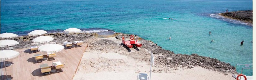 The pale sandy beach seen from the kiosk, with sunloungers in rows