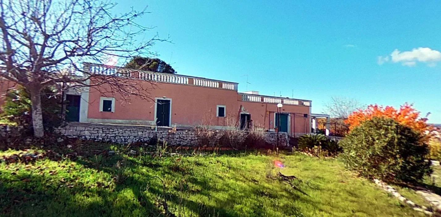 The villa seen from the garden, with the dry-stone wall and the terrace balustrade